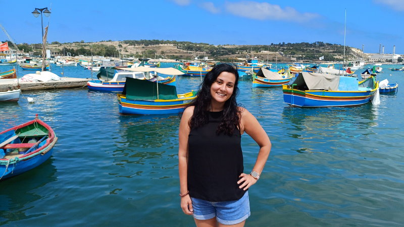 Infirmière italienne souriante, heureuse, posant face à la mer et aux bateaux à Malte, sous le soleil